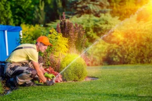 A man watering a green lawn with sprinkler system