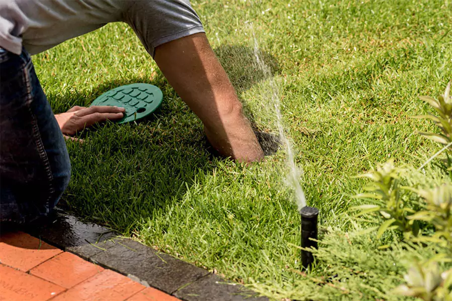 A Sprinkler Repair Man repairing sprinkler in the landscape in Humble, TX