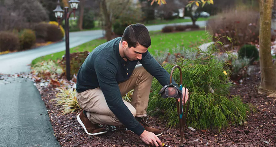 A professional installing path lighting in a landscaped area in Humble, TX.