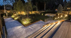 Modern garden pathway with ambient lighting and wooden deck stairs in Humble, TX, by Texas Rainmakers.